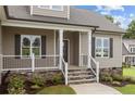 Inviting front porch with stone base, white pillars, and landscaped garden beds leading to the entrance at 75 Woodbark Cv # 10, Willow Springs, NC 27592