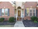 Charming entryway with a wood door, brick facade, and seasonal decorations at 9404 Perimeter Ct, Zebulon, NC 27597