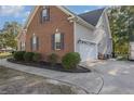 Side view of a brick home with a two-car garage and well-maintained landscaping at 9404 Perimeter Ct, Zebulon, NC 27597