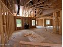 Expansive living room exhibiting exposed framing, a fireplace, and unfinished floors at 375 Graham Rd, Cameron, NC 28326