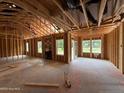 Spacious living room showcasing exposed framing, large windows, and unfinished floors at 375 Graham Rd, Cameron, NC 28326