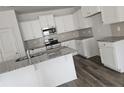 Modern kitchen with white cabinets, granite countertops, stainless steel appliances and wood look flooring at 8026 Royal Dr, Sanford, NC 27332