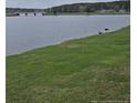 Scenic view of the pond with lush green grass and bridge in the distance at 8030 Turnberry Cir, Sanford, NC 27332