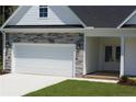 Charming home featuring stone accents, a two-car garage, manicured lawn, and covered entry way at 123 Nectar Ln, Bunnlevel, NC 28323