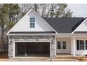 View of garage with stone accents and black roof at 123 Nectar Ln, Bunnlevel, NC 28323