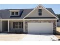 Well-built home with stone details, black shutters, a two-car garage, and a covered entryway at 174 Nectar Ln, Bunnlevel, NC 28323