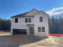 New construction featuring the home's frame covered in a moisture barrier, black roof, and front garage at 6200 Sheriff Watson Rd, Sanford, NC 27332