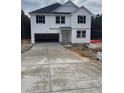 Newly built home with a long concrete driveway leading to an attached garage and a classic white facade at 6200 Sheriff Watson Rd, Sanford, NC 27332