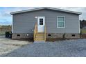 Rear view of gray manufactured home with wooden steps and landscaping at 441 Hayes Rd, Spring Lake, NC 28390