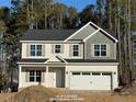 Attractive two-story home with tan siding, a two-car garage, and a classic architectural design at 78 Bennett Rd, Coats, NC 27521