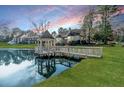 Picturesque pond featuring a charming gazebo, reflecting a sunset sky and surrounding homes at 2648 Buckingham Dr, Sanford, NC 27330