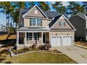 Charming two-story home with a covered front porch and two-car garage on a sunny day at 137 Falls Creek Dr, Spring Lake, NC 28390