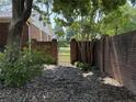 Backyard brick wall with metal door and surrounding trees, creating a private and tranquil outdoor space at 307 Westfield Dr, Dunn, NC 28334