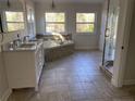 Bright main bathroom with dual sink vanity, large soaking tub, walk-in shower, and tile flooring at 307 Westfield Dr, Dunn, NC 28334