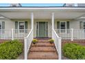 Brick steps leading up to a charming front porch with white railings and a green door at 1003 Kelly Dr, Nashville, NC 27856