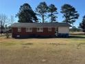 View of the backyard, showcasing the home's brick exterior and ample green space at 108 George St, Dunn, NC 28334