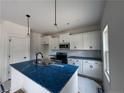 Bright kitchen featuring a sink in the island with a blue countertop, pendant lighting, and white cabinets at 24 Tackett Ct, Lillington, NC 27546