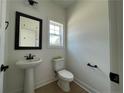 Stylish powder room with a pedestal sink, toilet, dark fixtures, and a framed mirror at 24 Tackett Ct, Lillington, NC 27546