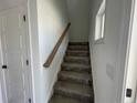 Bright stairway featuring carpeted steps and a wooden handrail leading to the upper level of the home at 24 Tackett Ct, Lillington, NC 27546