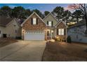 Charming two-story home at twilight with a two-car garage and stone and siding exterior at 55 London Way, Spring Lake, NC 28390