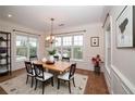 Bright dining room with hardwood floors, wainscoting, a modern chandelier, and views of the outdoors at 1222 Waterford Lake Dr, Cary, NC 27519
