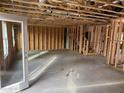 Exposed framing and bare concrete floors in an unfinished room; open to stairs and a view to the exterior at 36 Horse Trot Ln, Sanford, NC 27330