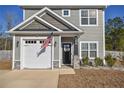 Close-up of a charming two-story home with gray siding, a black door, an American flag, and a well-maintained front yard at 206 Westpark Ln, Sanford, NC 27332