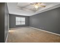Spacious main bedroom featuring plush carpeting, tray ceiling, and a large window at 323 River Oak St, Spring Lake, NC 28390