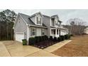 View of the home with light gray siding, a white garage door, and neat landscaping on a spacious lot at 216 Cobblestone Dr, Spring Lake, NC 28390