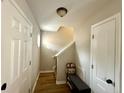 Bright hallway with hardwood floors, white doors, and a bench with storage, leading to the staircase at 216 Cobblestone Dr, Spring Lake, NC 28390