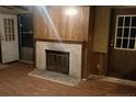 Living room featuring hardwood floors, wood paneling, and a classic brick fireplace at 22176 Nc 24-27, Cameron, NC 28326