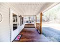 Covered front porch with a stained wood floor, porch swing, and wooded views at 476 Riddle Rd, Sanford, NC 27330