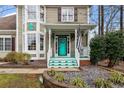 Inviting front porch showcasing a turquoise door, detailed trim, and a well-maintained walkway with landscaped surroundings at 214 Pine Nut Ln, Apex, NC 27502