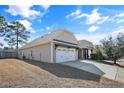 A beige home featuring a three-car garage and a well-manicured yard with mature trees and shrubs at 31 Laurel Dr, Spring Lake, NC 28390