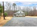 Quaint home with a covered porch, surrounded by a serene landscape and a spacious gravel driveway at 3208 Westchester Dr, Sanford, NC 27330