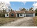 Inviting one-story home boasts a brick-accented entrance, white siding, and a long driveway leading to the attached garage at 1425 Ponderosa Trl, Cameron, NC 28326