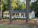 Attractive one-story house with white painted brick, attached garage, and surrounded by mature trees and landscaping at 374 S Denise Ave, Coats, NC 27521