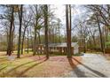 A cozy brick home nestled among trees with an attached garage and long driveway at 374 S Denise Ave, Coats, NC 27521