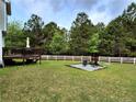 Large backyard with a deck, fire pit area, and a white picket fence bordering the wooded area, ideal for entertaining at 11 Scotland Dr, Spring Lake, NC 28390