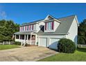 Two-story home with a two-car garage, front porch with white railing, and mature trees surrounding the property at 11 Scotland Dr, Spring Lake, NC 28390