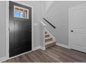 Inviting foyer with wood-look flooring, a black door and a staircase with carpeted steps at 165 Mahogany Ct, Cameron, NC 28326