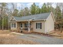 Well-kept home with neutral siding, a cozy front porch, and a gravel driveway nestled among the trees at 640 Lanier Farm Rd, Sanford, NC 27330