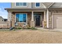 Inviting front porch with chairs, flower bed and stone accents enhance the entry at 100 Tripoli Dr, Cameron, NC 28326