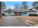 Single story light blue home with an attached garage, brick decor, and a gray shingled roof at 95 Fairway Ln, Sanford, NC 27332