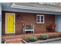 Welcoming brick front porch with a cozy swing bench and a bright yellow front door at 95 Fairway Ln, Sanford, NC 27332