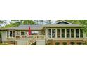 Relaxing backyard view showing deck with stairs, sunroom with many windows, and attractive yard at 95 Fairway Ln, Sanford, NC 27332