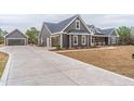 Grey home showcasing long driveway, 3 car garage, and landscaped lawn at 525 Sanctuary Trl, Cameron, NC 28326
