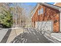 Spacious two-car garage attached to a brick home with a long driveway surrounded by lush trees at 105 Royal Glen Dr, Cary, NC 27518