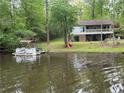 View of the waterfront home with a spacious backyard, boat dock, and lush greenery at 1393 Pennsylvania Ave, Sanford, NC 27332