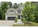 Charming two-story home with grey siding, black shutters, two-car garage and a well-manicured front lawn at 718 Creekside Dr, Sanford, NC 27330